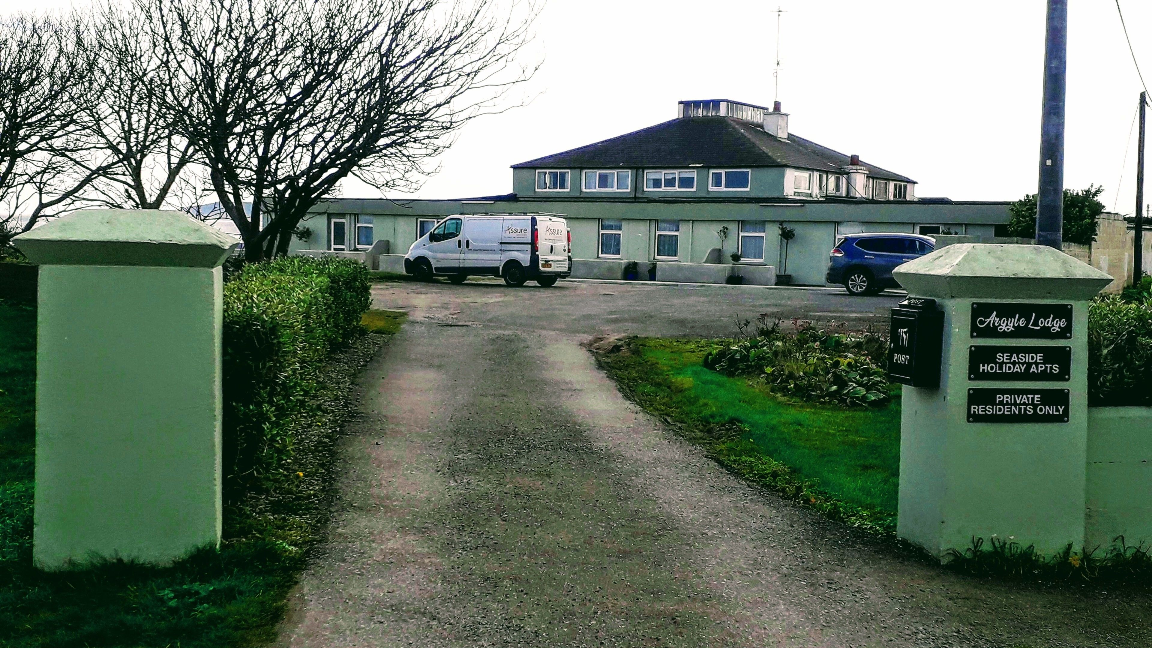 Un vialetto chiuso da cancello conduce a un edificio con un cartello che indica 'Argyle Lodge' e 'Solo Residenti Privati'.