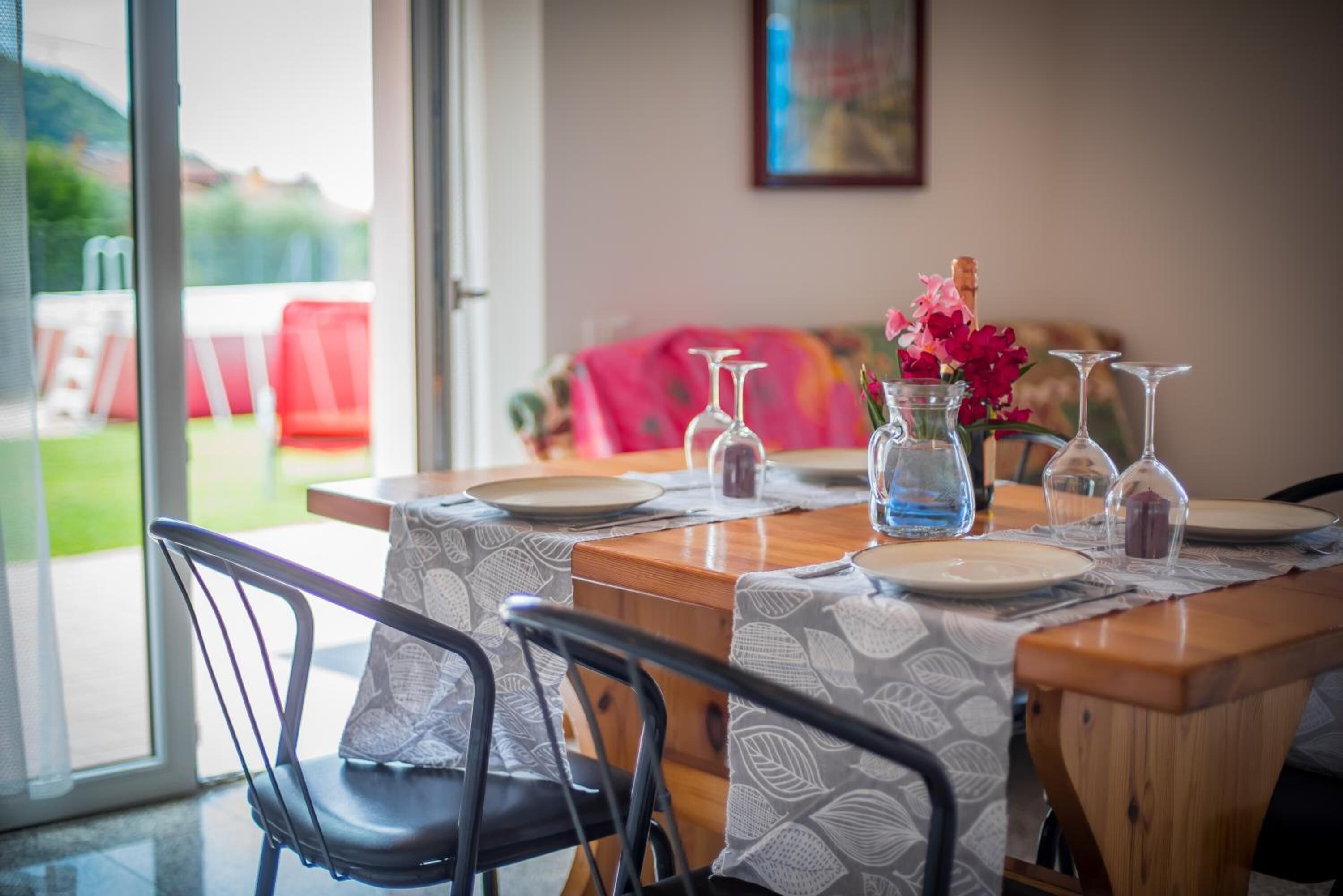 A dining table set with plates, glasses, and a vase with flowers.