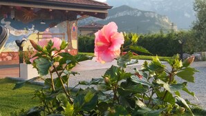 Ein Gebäude mit Wandgemälde, einer großen, rosafarbenen Blume und einer Bergkulisse.