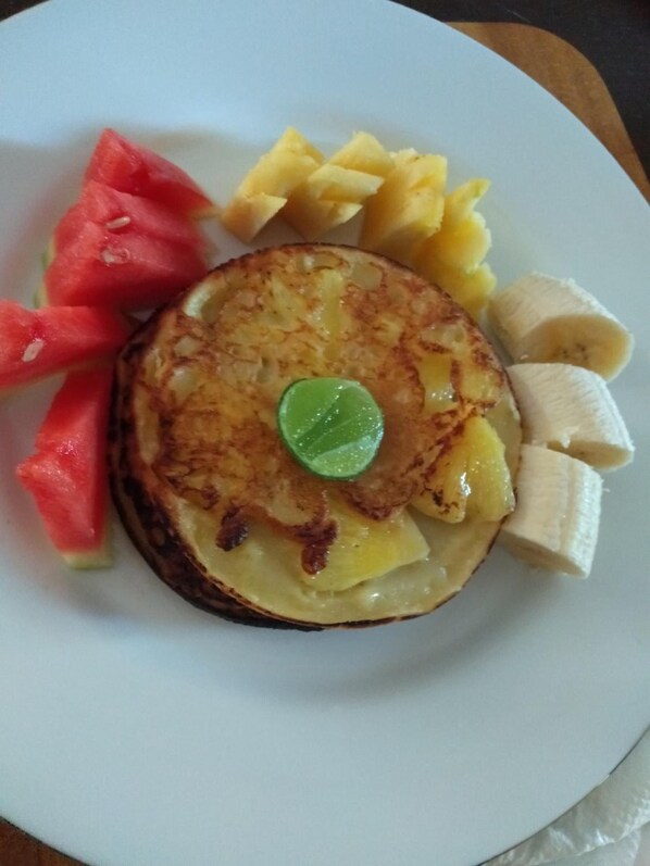 Un plato con tortitas, sandía, piña, plátano y una cuña de lima.