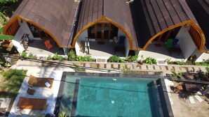 A residential complex with multiple houses featuring curved roofs and a central swimming pool. - Macoa Village (Gili Trawangan)
