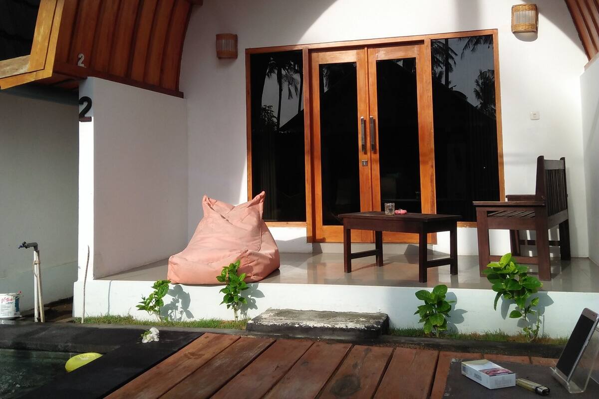 A wooden deck with a table and chairs, a small garden area with plants, and a water feature.