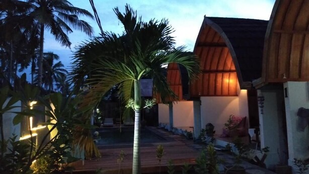 A modern building with a curved roof and a wooden deck. - Macoa Village (Gili Trawangan)
