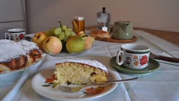 Ein Tisch mit Kuchenstück, Obstteller, Tasse und Teekanne.
