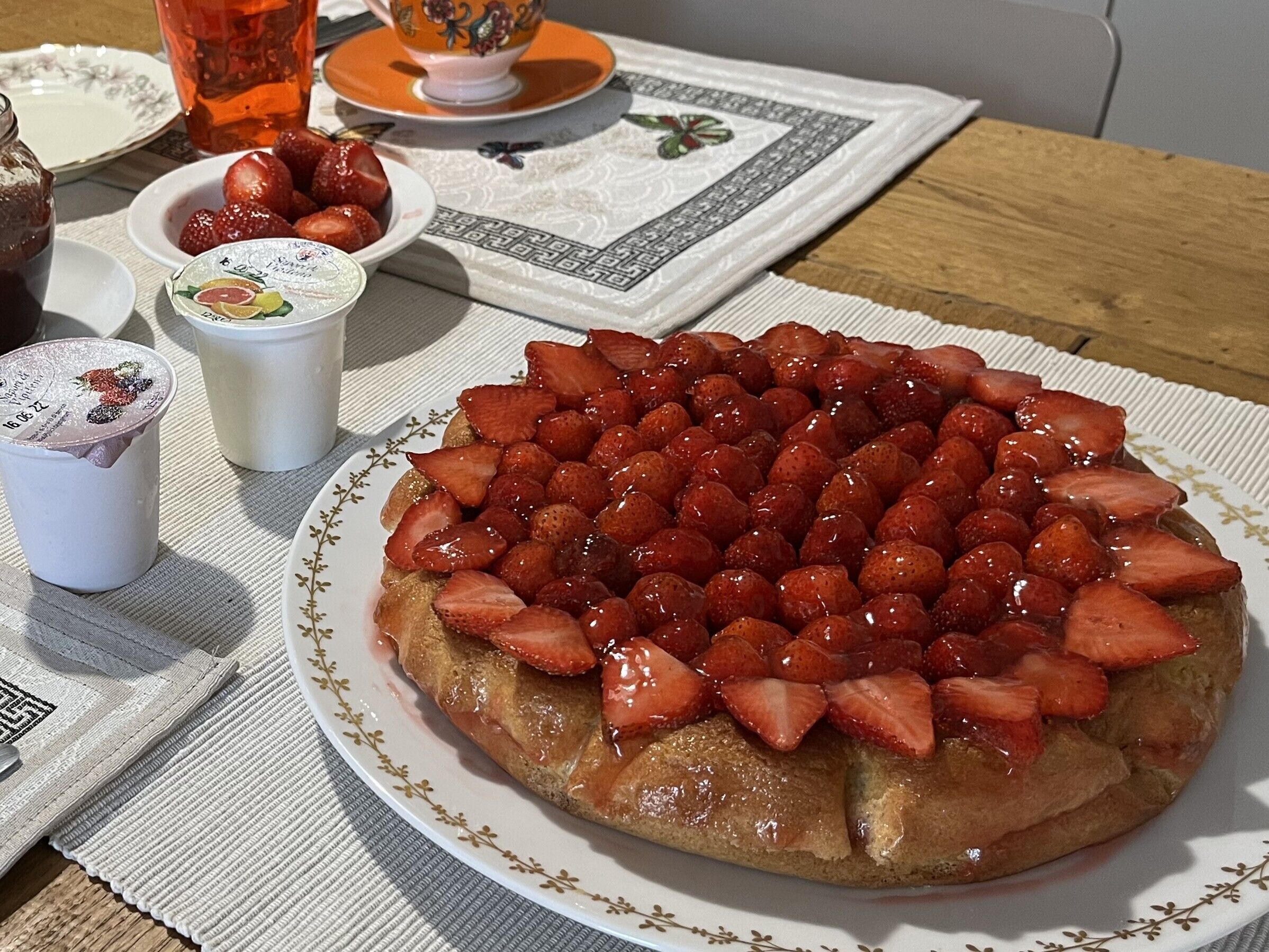 Un piatto di fragole su pane tostato, con una tazza di tè e un bicchiere d'acqua su un tavolo.