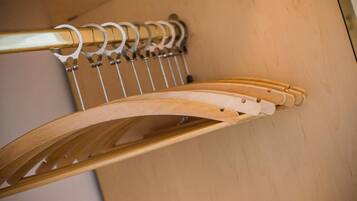 A wooden chair with a curved backrest and metal hooks on a wall.