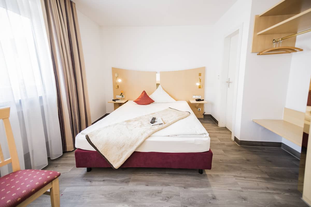 Een hotelkamer met een bed, nachtkastjes, een bureau, een stoel en een kledingkast.