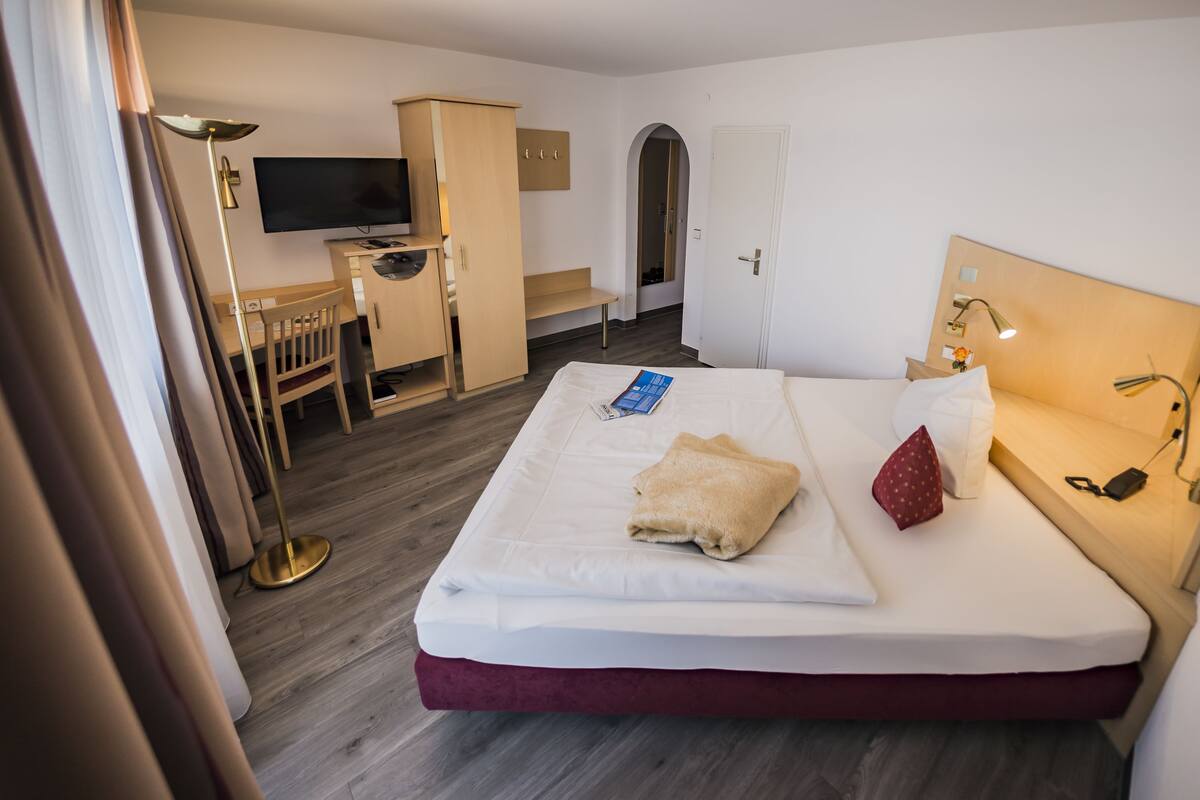 Een hotelkamer met een bed, bureau, televisie en een kledingkast.