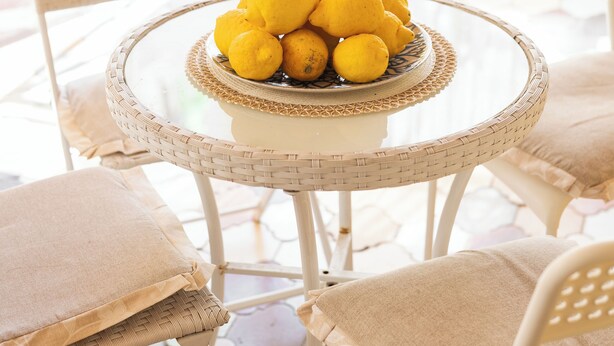 A round table with a bowl of lemons, wicker chairs, and a tiled floor. - L'anfiteatro di Pompei B&B (Pompei)