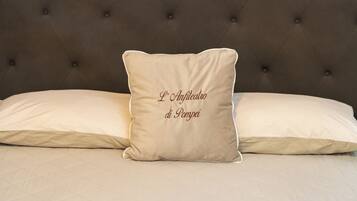 A bedroom with a tufted headboard, a bed with two pillows, and a colorful abstract painting on the wall.