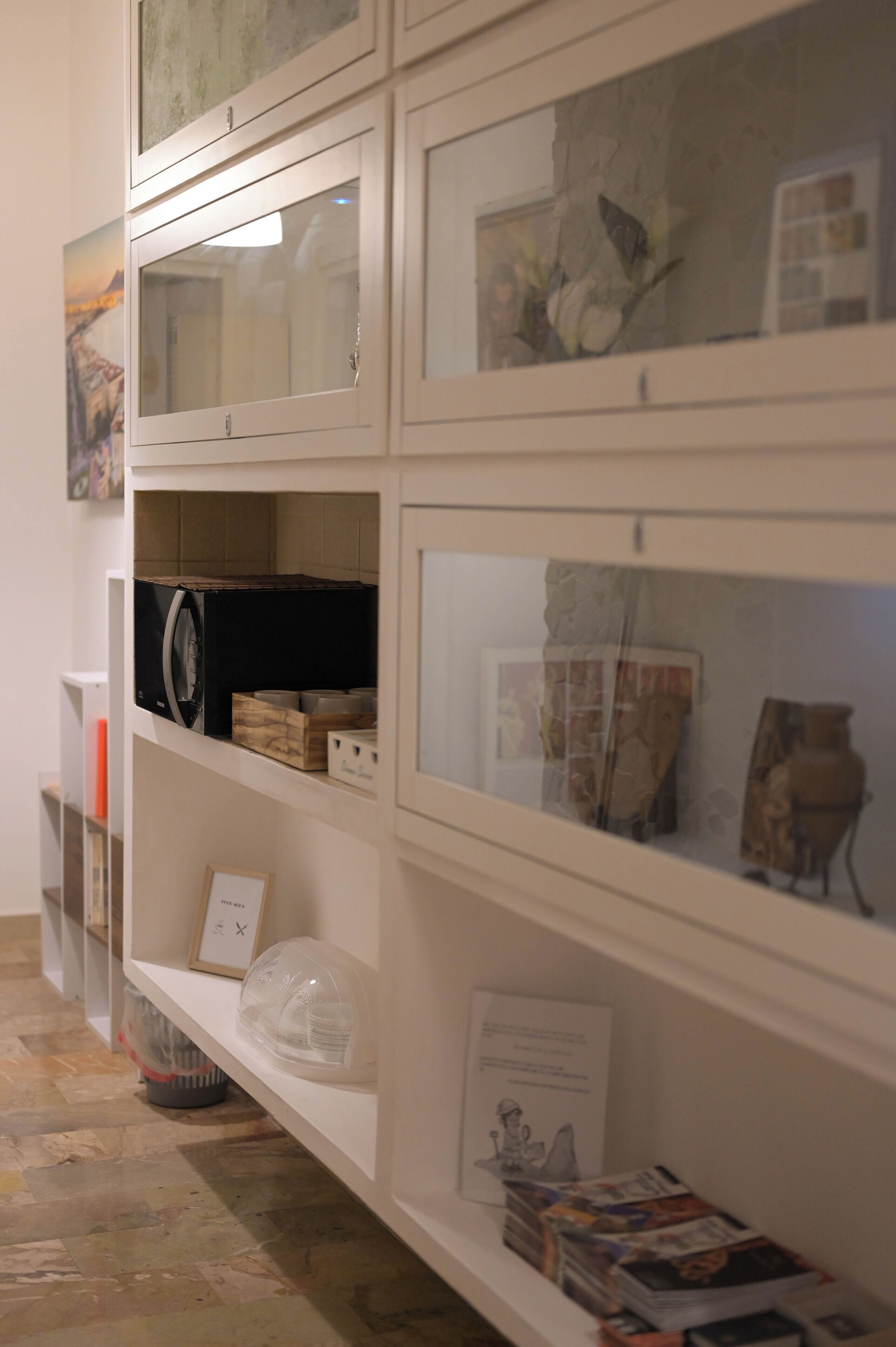 A display of various items including books, a black refrigerator, and framed artwork on shelves.