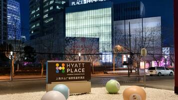 A Hyatt Place sign with a large illuminated display, surrounded by decorative spheres, in front of a modern building with reflective glass windows.