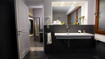 A modern bathroom with a large mirror, a white sink, and a towel rack.