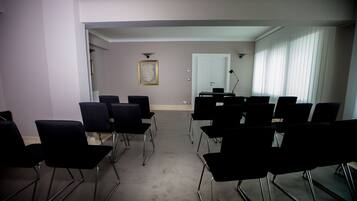 A conference room with rows of black chairs, a white door, and a framed picture on the wall.