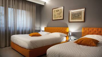 A hotel room with two beds, a large window with curtains, and two framed maps on the wall.