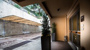 A modern building entrance with a concrete wall, a metal roof, and a potted plant. - Principessa Mafalda (Messina)