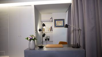 A modern office space with a desk, a vase with flowers, a bookshelf, and a framed picture on the wall.