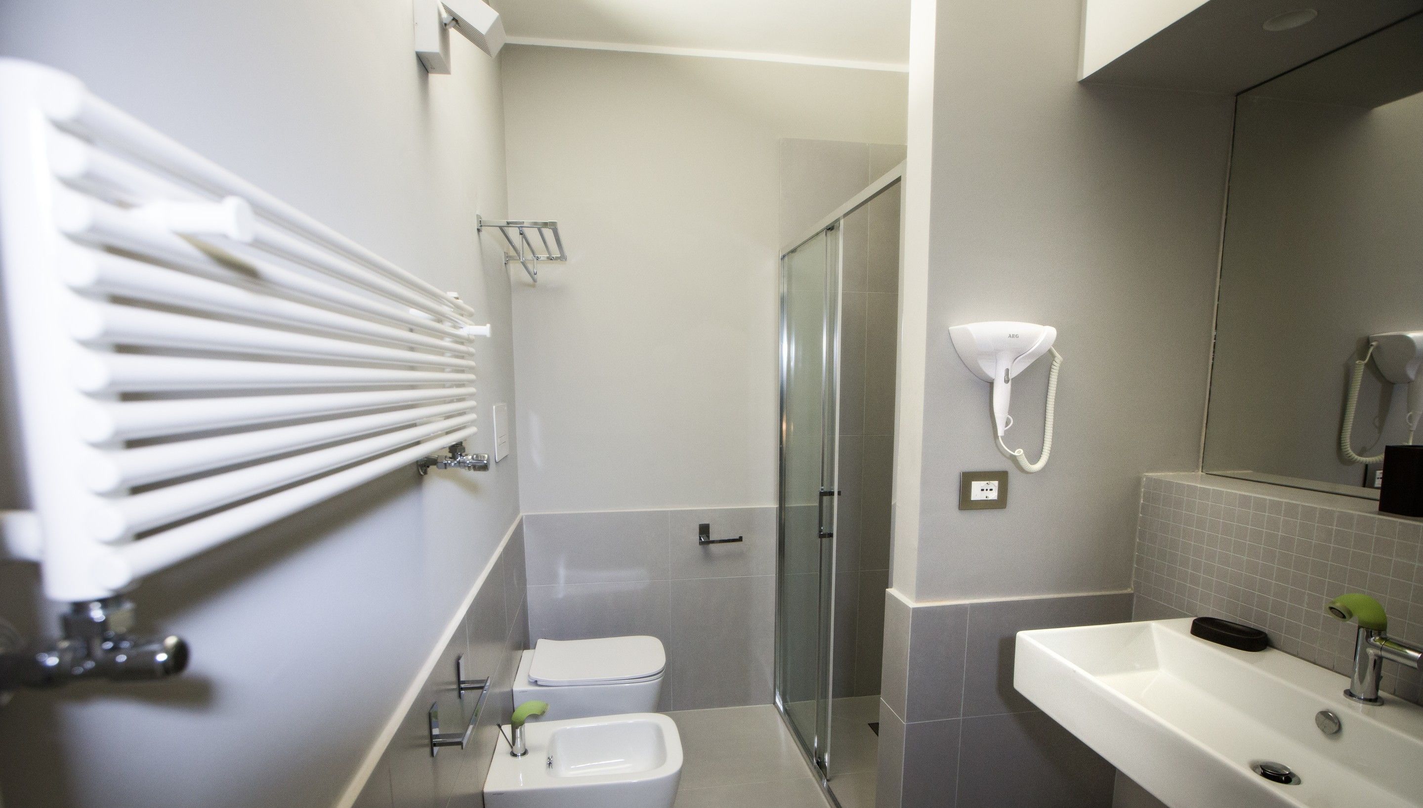 Une salle de bain moderne avec une douche à parois de verre, un lavabo blanc et un porte-serviettes.