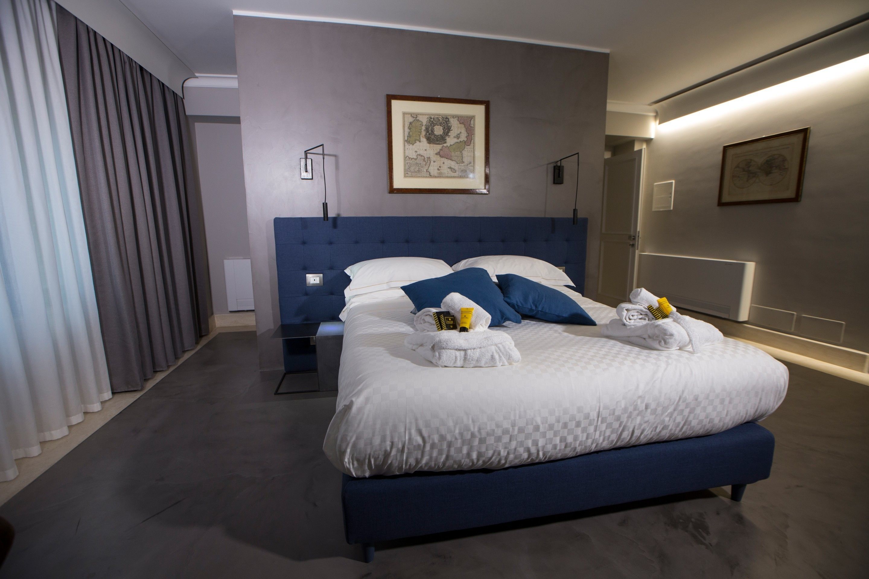 Une chambre d’hôtel moderne avec un grand lit, une table de chevet, une lampe et un tableau encadré au mur.