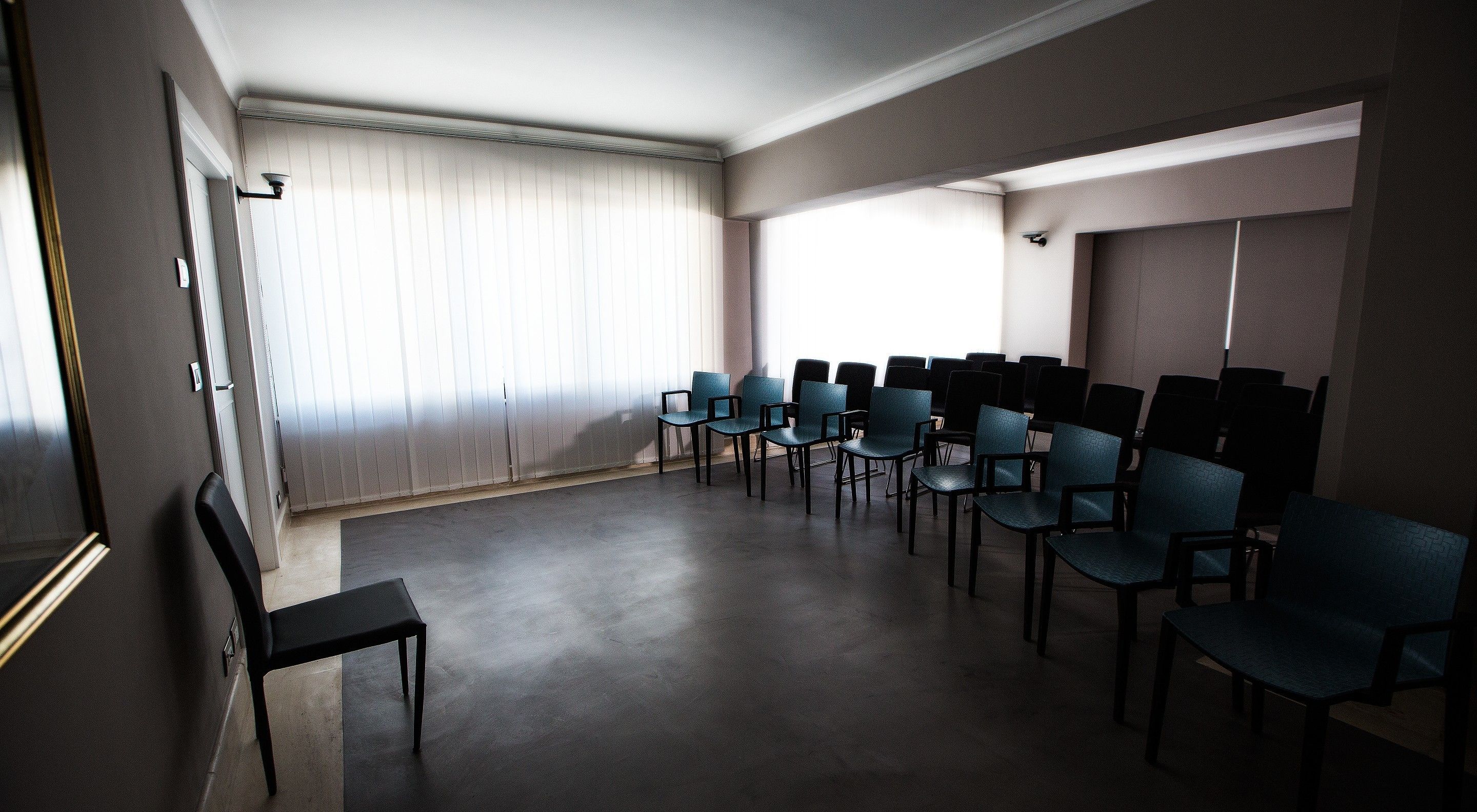 A conference room with rows of chairs, a small table, and a window with blinds.