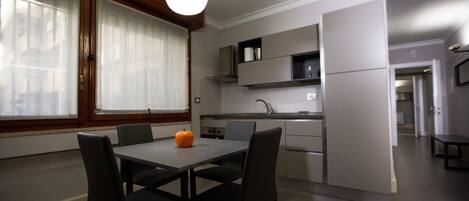 A modern kitchen with a dining table and chairs, a refrigerator, and built-in cabinets.