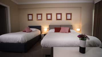 Ein Hotelzimmer mit zwei Betten, einem Nachttisch und einer Wand mit gerahmten Bildern.