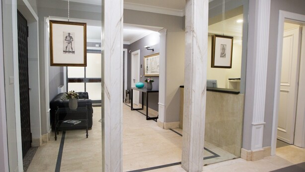 A hallway with framed artwork on the walls, a black sofa, and a coffee table with a vase. - Principessa Mafalda (Messina)