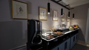 A buffet setup with a coffee machine, various food items, and framed artwork on the wall. - Principessa Mafalda (Messina)