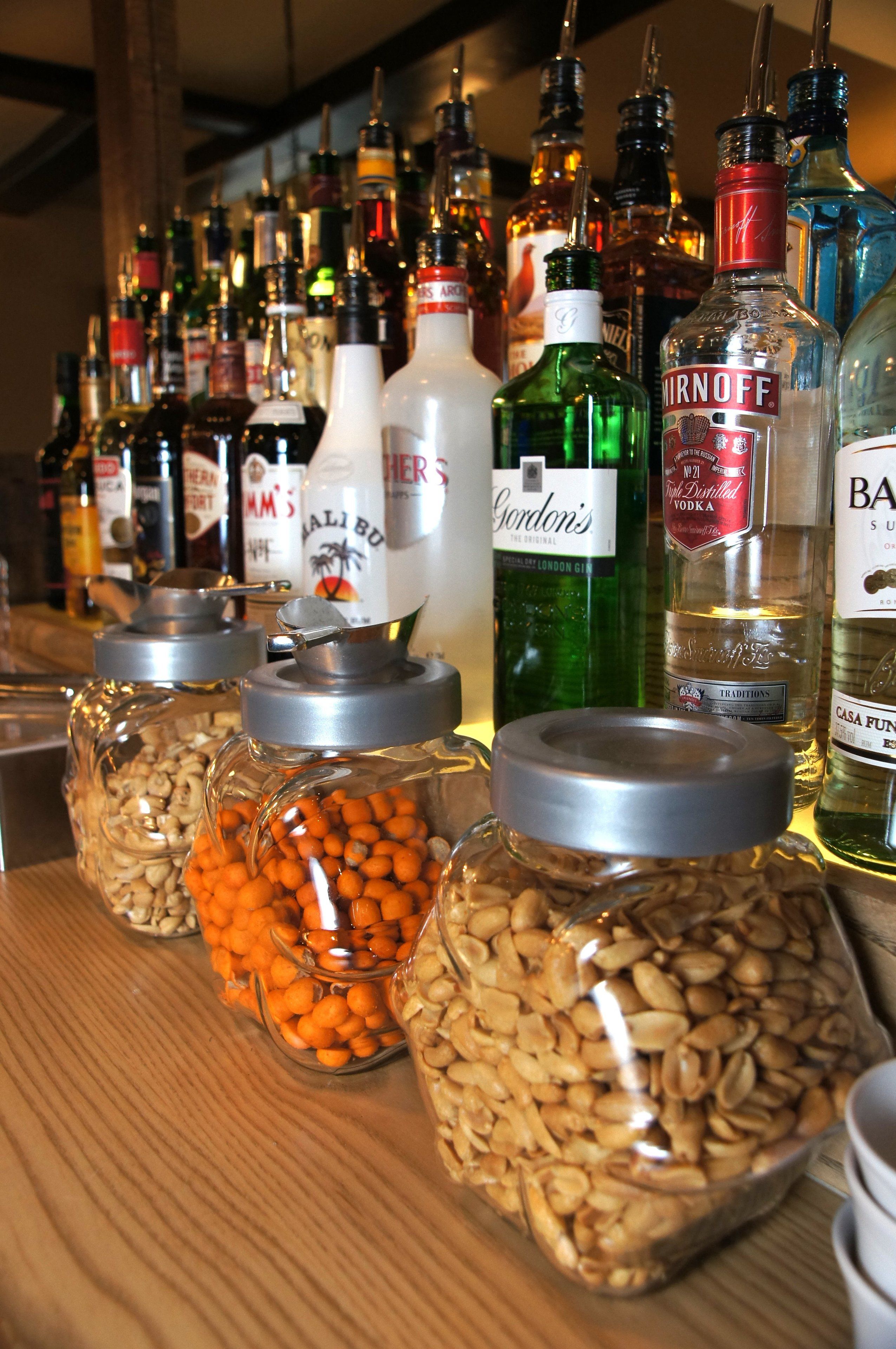 A bar with various bottles of alcohol and jars of nuts.