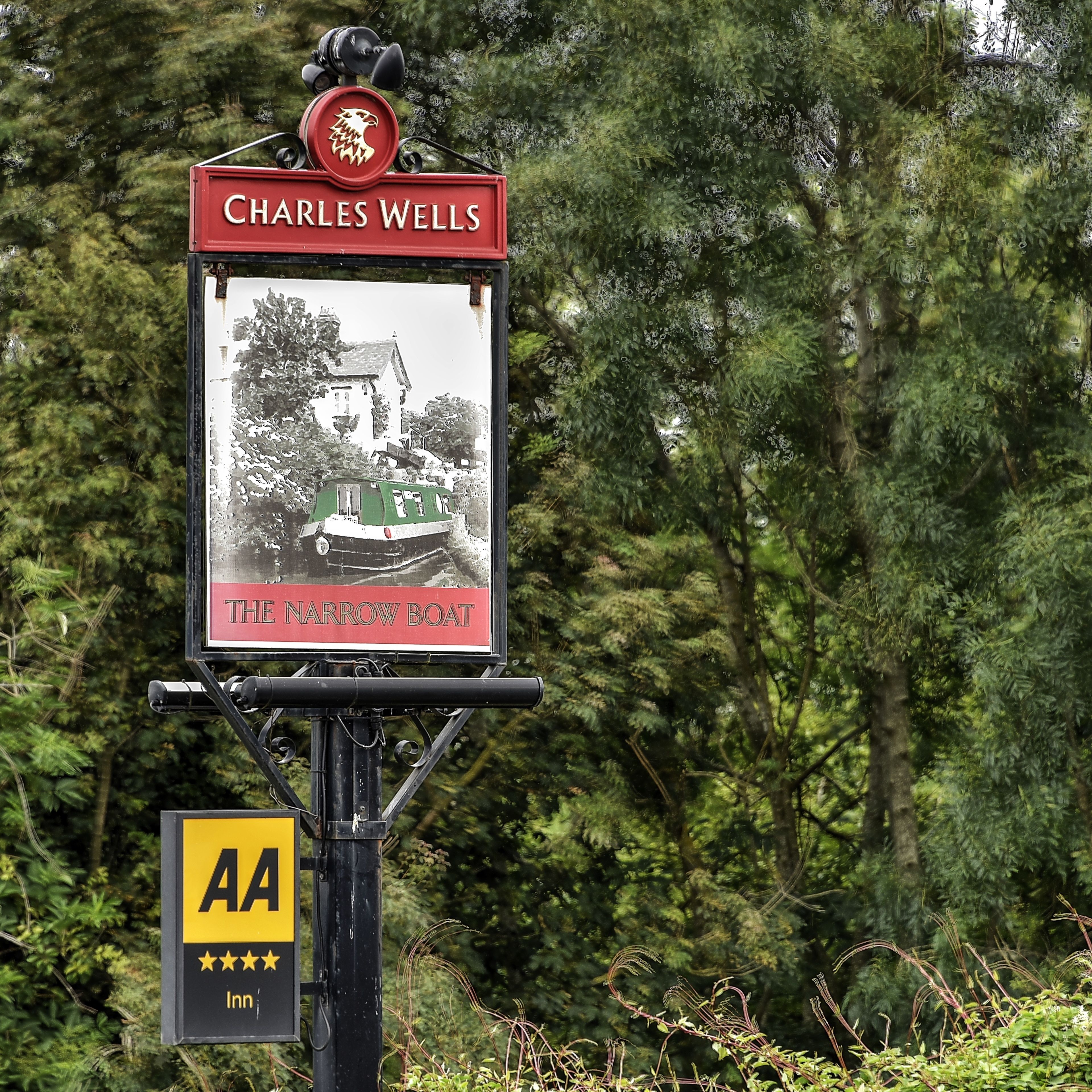 A sign for Charles Wells Inn with a historical photo of a narrow boat.