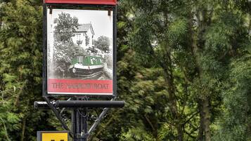 A sign for Charles Wells Inn with a historical photo of a narrow boat.