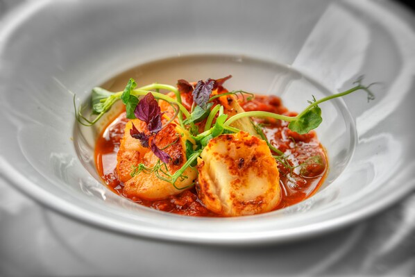 A dish with seared scallops, garnished with microgreens and herbs, served on a white plate. - The Narrowboat At Weedon (Northampton)