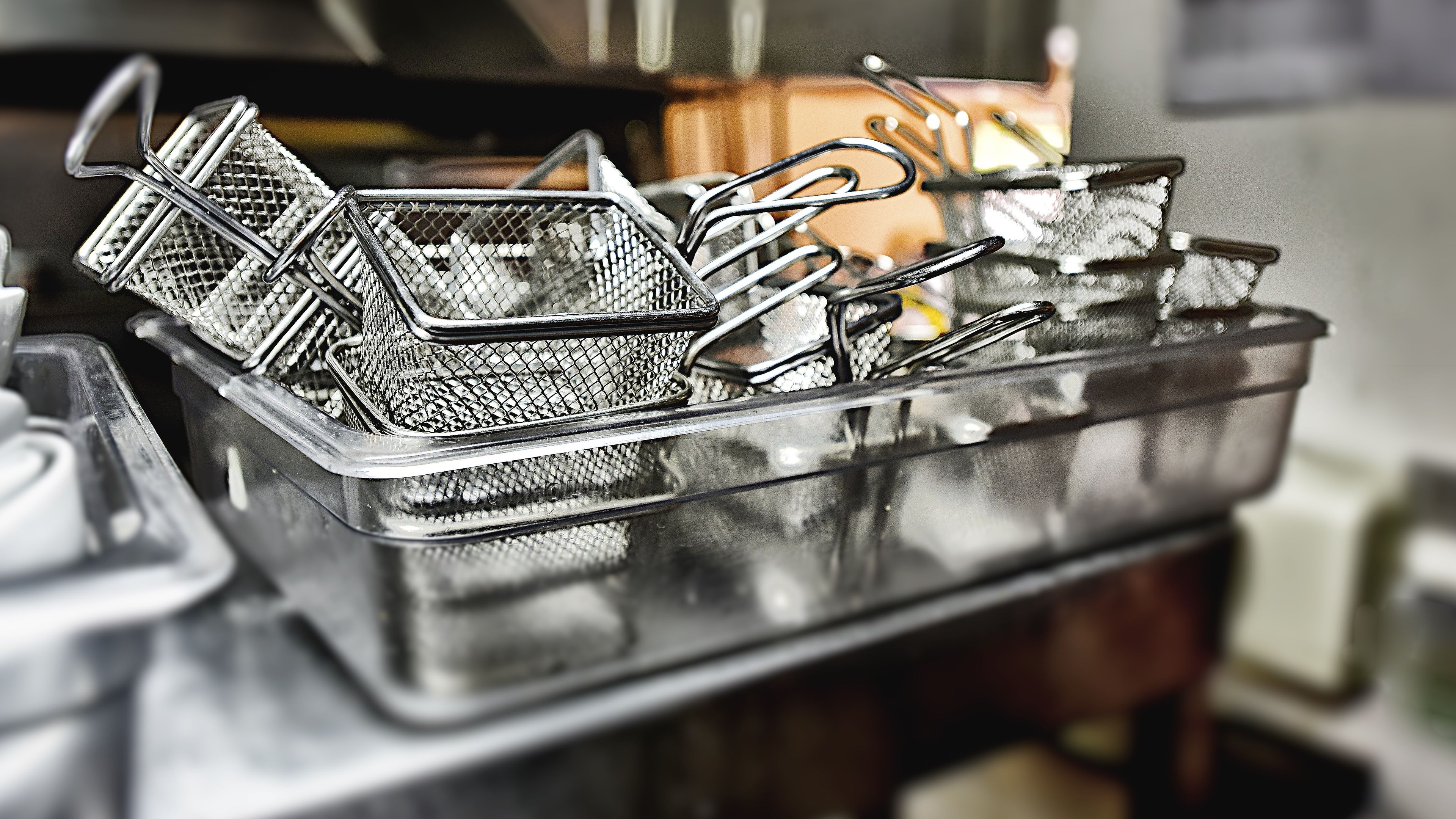 A metal basket filled with metal mesh containers, likely used for holding kitchen utensils.