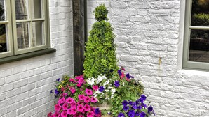 A white brick building with a window and a planter with colorful flowers. - The Narrowboat At Weedon (Northampton)