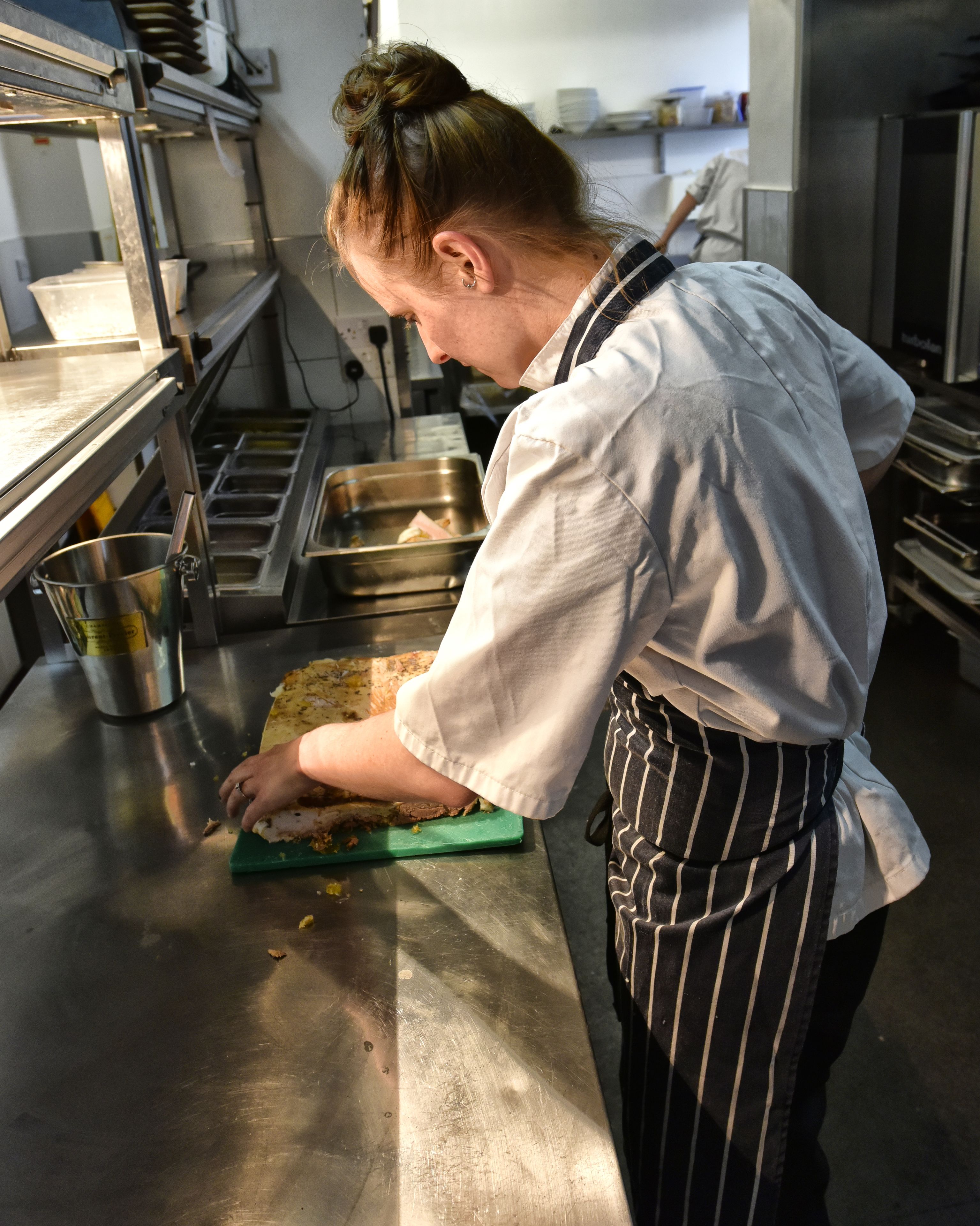 A person in a kitchen preparing food on a cutting board.