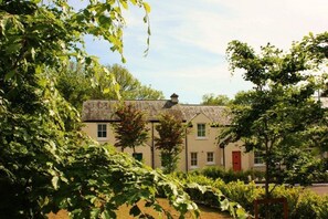 A building with a pitched roof, multiple windows, and a red door. - Bunratty Castle Gardens Home (Bunratty)