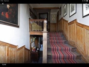 A staircase with a striped carpet, wooden railings, and a small balcony with a chair. - Harlington Manor (Dunstable)