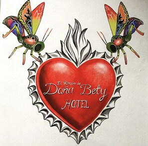 A red heart-shaped sign with the text "El Rincon de Dora Betty HOTEL" surrounded by a decorative border. - El Rincon de Doña Bety (Oaxaca)