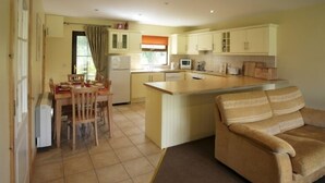 A compact kitchen with a dining area, a sofa, and a small island. - Ballylickey Bay Holiday Home (Bantry)