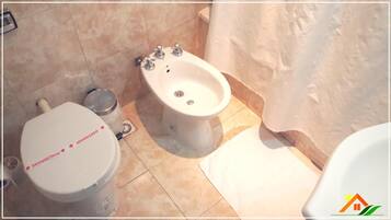 Un baño con inodoro, bidé y zona de ducha.