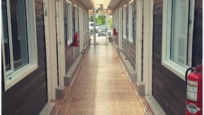 A corridor with wooden ceiling beams, tiled flooring, and windows on both sides. - Meraki Hotel (Las Heras)