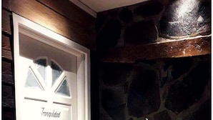 A white door with the word "Tranquilidad" on it, a stone wall, and a vase with dried plants on a stone floor. - Meraki Hotel (Las Heras)