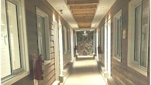 A long, narrow hallway with wooden floors and a high ceiling. - Meraki Hotel (Las Heras)