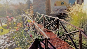 A wooden bridge with metal railings in a garden setting. - Hosteria el Puente (Merlo)