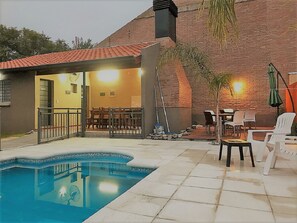 Een buitenzwembad, ligstoelen bij het zwembad