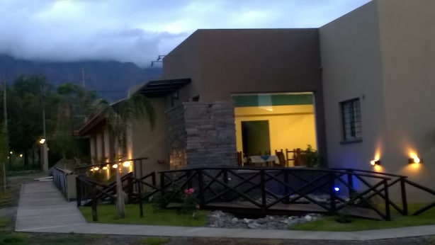 A modern building with a stone facade, a wooden deck, and a view of the mountains in the background. - Hosteria el Puente (Merlo)