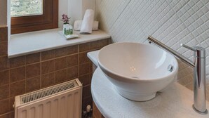A bathroom with a large sink, a window, a radiator, and a mirror.