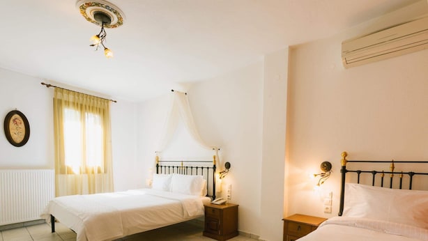 A hotel room with two beds, a radiator, a window with curtains, and a wall-mounted air conditioner.