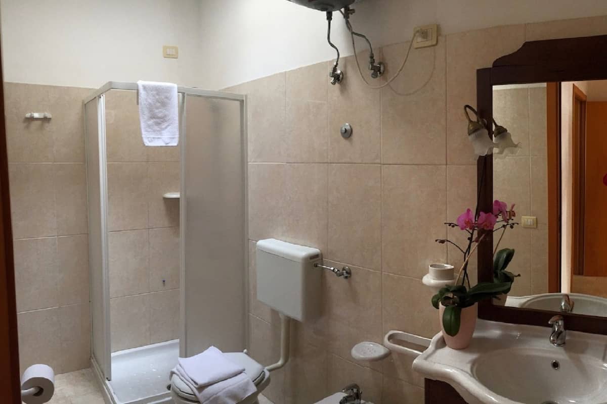 Un baño con ducha, inodoro, bidé, lavabo y espejo.