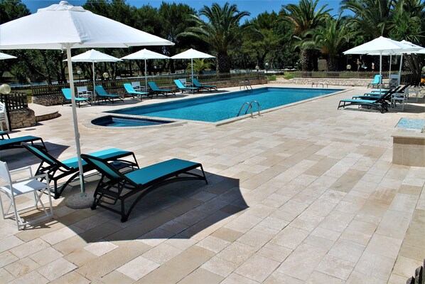 A pool area with lounge chairs and umbrellas.
